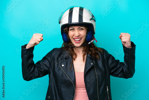 Young caucasian woman with a motorcycle helmet isolated on blue background doing strong gesture © luismolinero