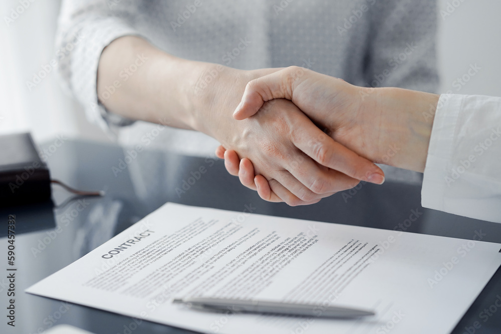 Business people signing contract papers while sitting at the glass table in office, closeup. Partners or lawyers working together at meeting. Teamwork, partnership, success concept