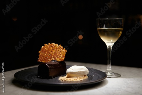 Tapet Plate of chocolate and white dessert next to a glass of white whine on a table
