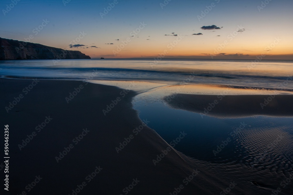 Obraz premium Maslins beach at dawn with fiery and purple clear sky backkground