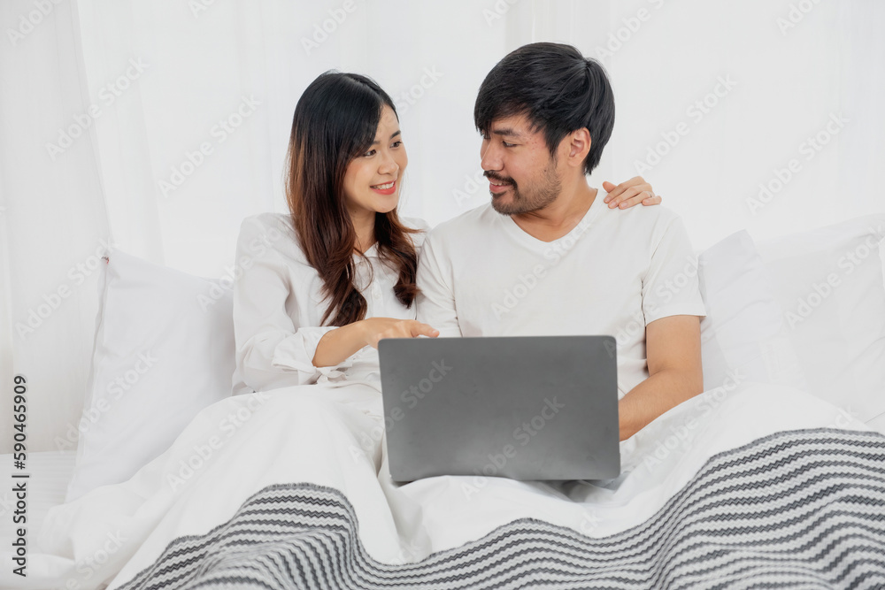 Young happy asian couple using laptop in bed watching movie, romantic time to enhance family relationship, family concept. Young happy asian couple using laptop in bed watching movie, romantic time to enhance family relationship, family concept.