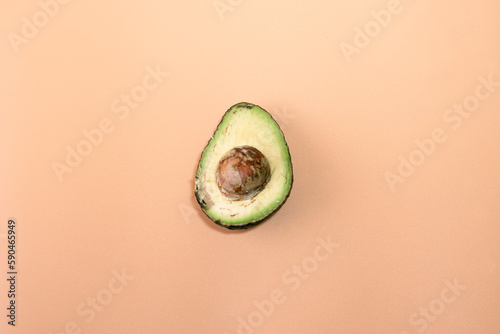 A rotten avocado cut in half on a colored background. The avocado is rotten and no longer good to eat.
