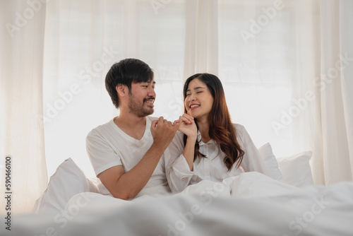 Happy young asian couple embracing, teasing, playing cheerfully in bed at home, romantic time to enhance family bonding. family concept.