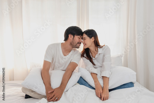 Happy young asian couple embracing, teasing, playing cheerfully in bed at home, romantic time to enhance family bonding. family concept. © PHAISITSAWAN