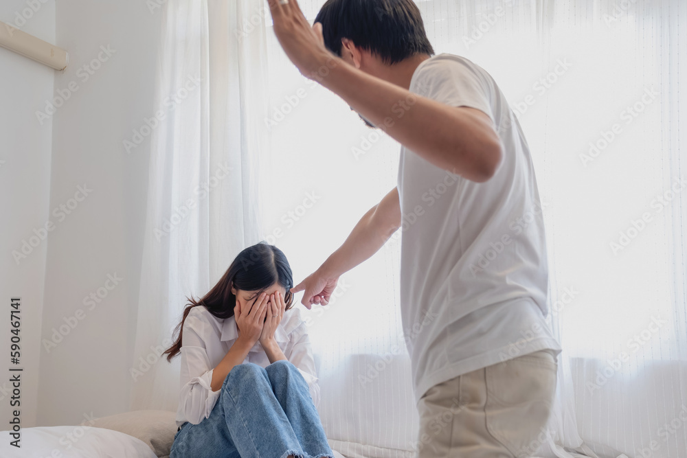 Internal violence. family conflict Men attack and beat women at home. Frightened woman covering her face sitting on the bed. She was scared. Internal violence. family conflict Men attack and beat women at home. Frightened woman covering her face sitting on the bed. She was scared.