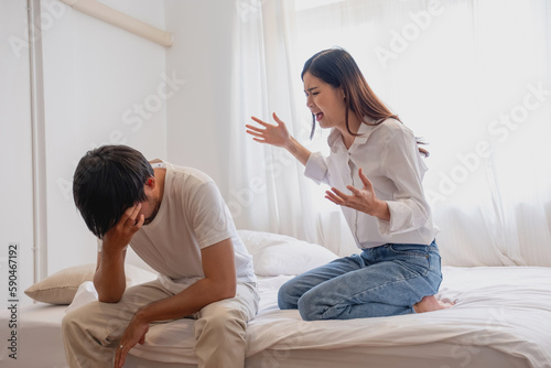 Internal violence. family conflict A woman is violently reprimanding her husband in an angry mood. make the husband feel bad In the bed inside the house, family quarrel concept.