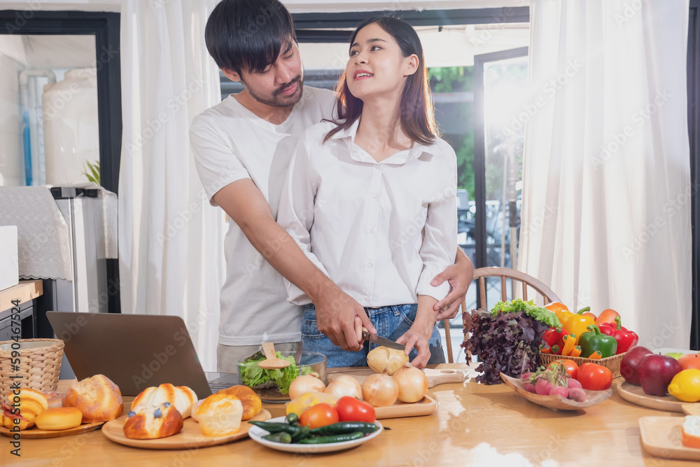 Young Asian couple cooking with fruits and vegetables and using laptop in the kitchen To cook food together within the family happily, family concept. Young Asian couple cooking with fruits and vegetables and using laptop in the kitchen To cook food together within the family happily, family concept.