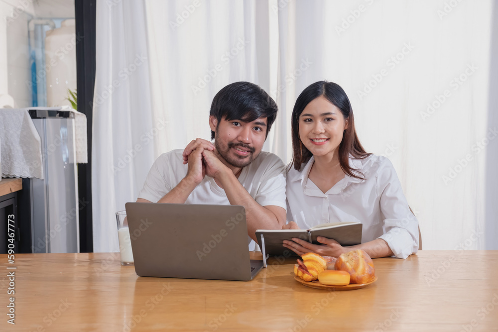 Young Asian couple cooking with fruits and vegetables and using laptop in the kitchen To cook food together within the family happily, family concept. Young Asian couple cooking with fruits and vegetables and using laptop in the kitchen To cook food together within the family happily, family concept.