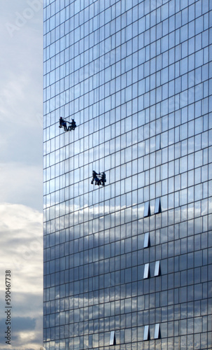 A Two Climbing Workers Clean the Windows on Skyscraper