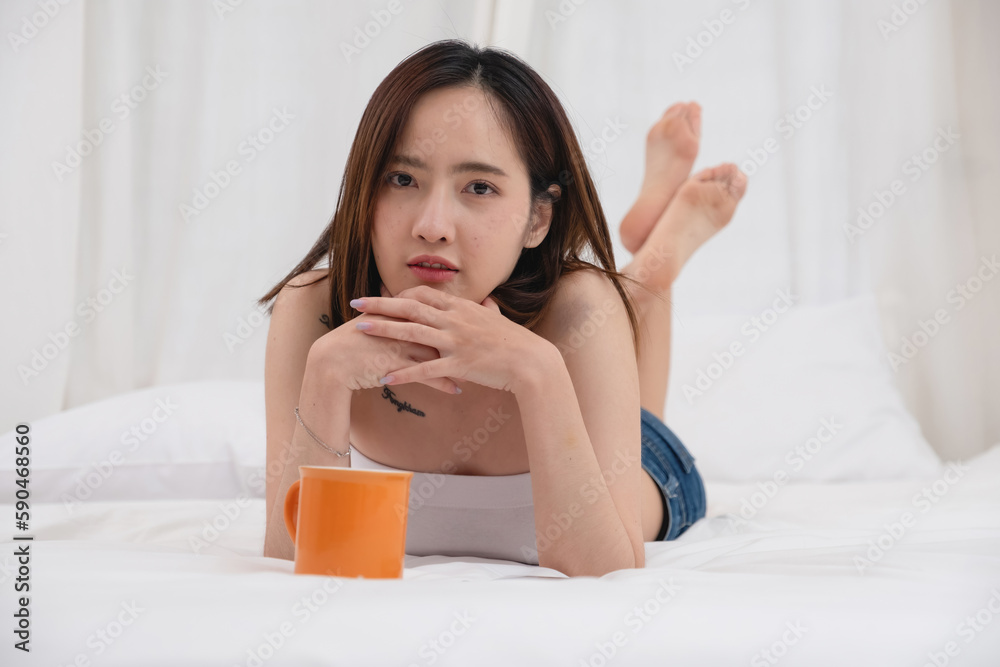 Portrait of white Asian woman with tattoo resting in bed to rest and relax inside white bedroom on her holiday, holiday morning concept. Portrait of white Asian woman with tattoo resting in bed to rest and relax inside white bedroom on her holiday, holiday morning concept.