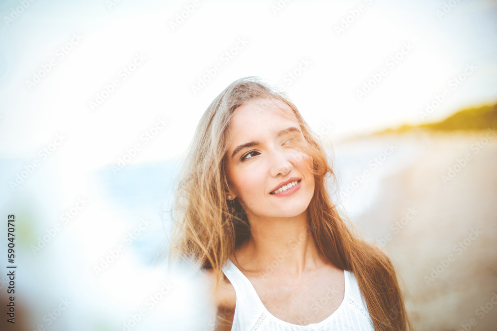 Portrait of a happy smiling woman in free happiness bliss on ocean beach enjoying nature during travel holidays vacation outdoors. View through white blurred flowers Portrait of a happy smiling woman in free happiness bliss on ocean beach enjoying nature during travel holidays vacation outdoors. View through white blurred flowers
