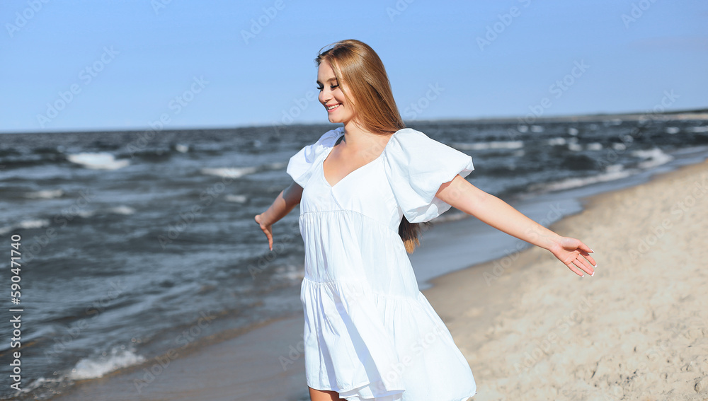 Happy smiling beautiful woman is on the ocean beach in a white summer dress, open arms Happy smiling beautiful woman is on the ocean beach in a white summer dress, open arms