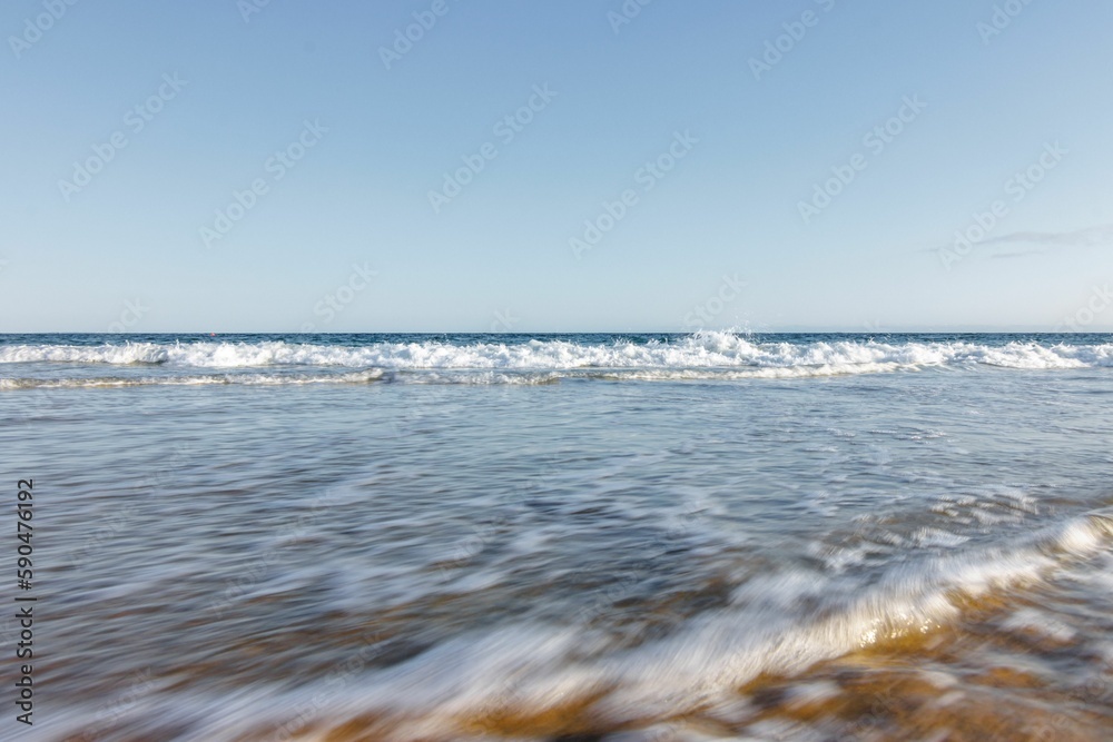 Soft ocean waves with foam on a sandy beach