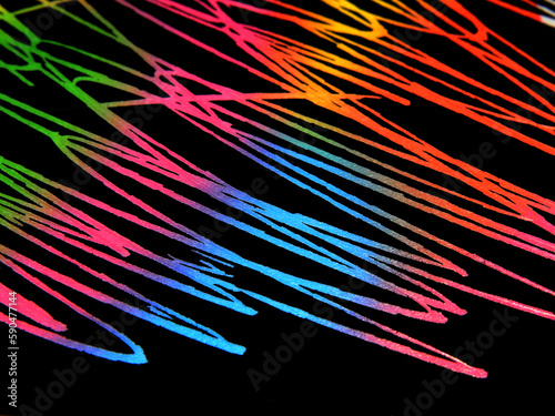 Multicolored writing pens on black paper texture