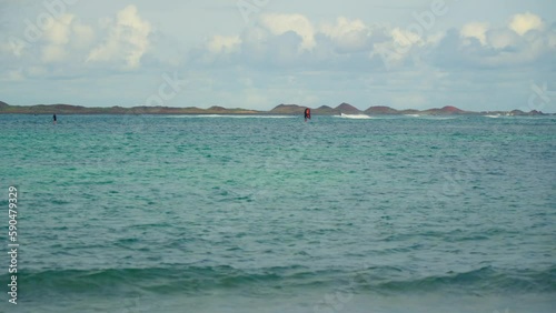 Wingfoil moves through blue water, on the horizon photo