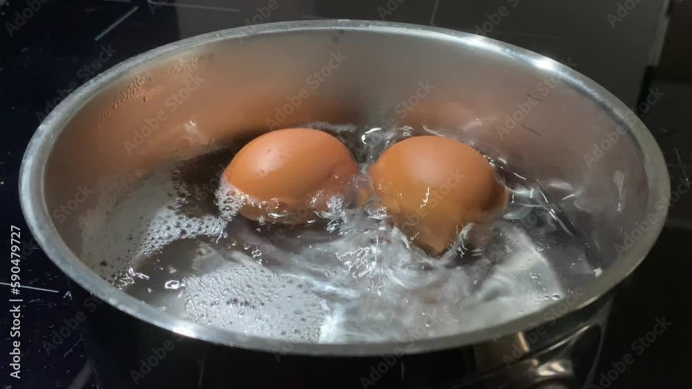 Chicken eggs in boiling water, close-up. Cooking food on an induction stove. Boiling water with chicken eggs in a saucepan.