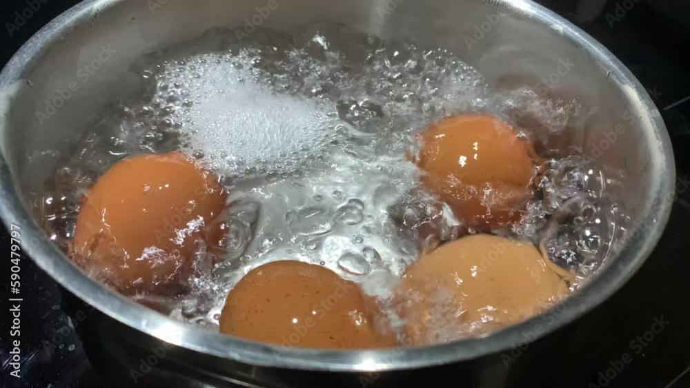 Chicken eggs in boiling water, close-up. Cooking food on an induction stove. Boiling water with chicken eggs in a saucepan. Chicken eggs in boiling water, close-up. Cooking food on an induction stove. Boiling water with chicken eggs in a saucepan.