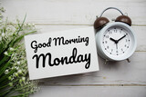 Good Morning Monday text message with flower and alarm clock on wooden background