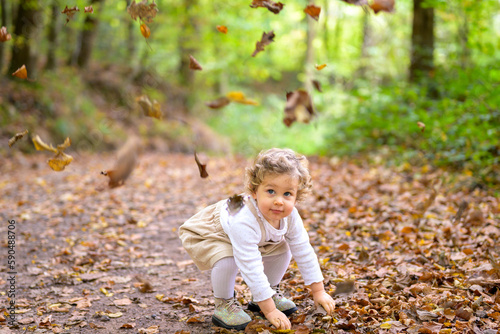 Little happy girl throwing leaves