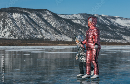 The mother with daughter is skating on the ice of Lake Baikal. Winter Siberian landscape.