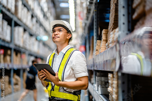 Warehouse Worker using digital tablets to check the stock inventory in large warehouses, a Smart warehouse management system, supply chain and logistic network technology concept.