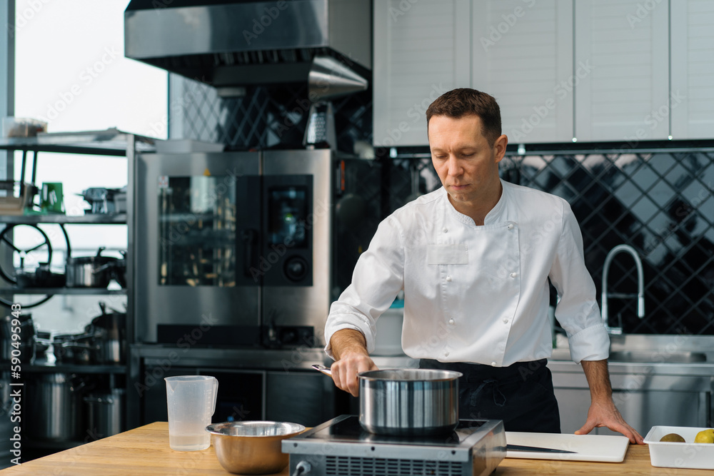 professional kitchen chef stirs hot oatmeal in a pot cooking breakfast healthy eating concept