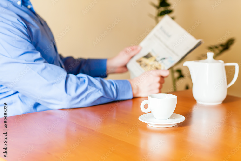Ein Kaffee trinkender Mann sitzt am Tisch und liest Zeitung. Ein Kaffee trinkender Mann sitzt am Tisch und liest Zeitung.
