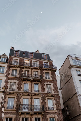 Exterior of aged residential building of beige color with glass windows and beautiful cast iron balconies located in the center of Paris, France © Elena Krivorotova