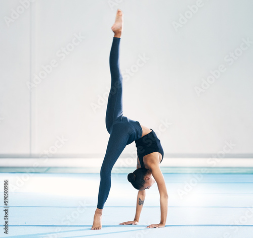 Gymnast, woman and cartwheel for training in gym, exercise and flexibility for mockup. Studio, performance and female athlete with somersault for gymnastics workout, sports competition or fitness.