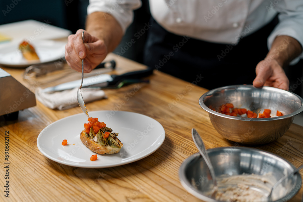 A professional chef puts roasted avocado and tomatoes on toast with spices pouring sauce over them healthy breakfast