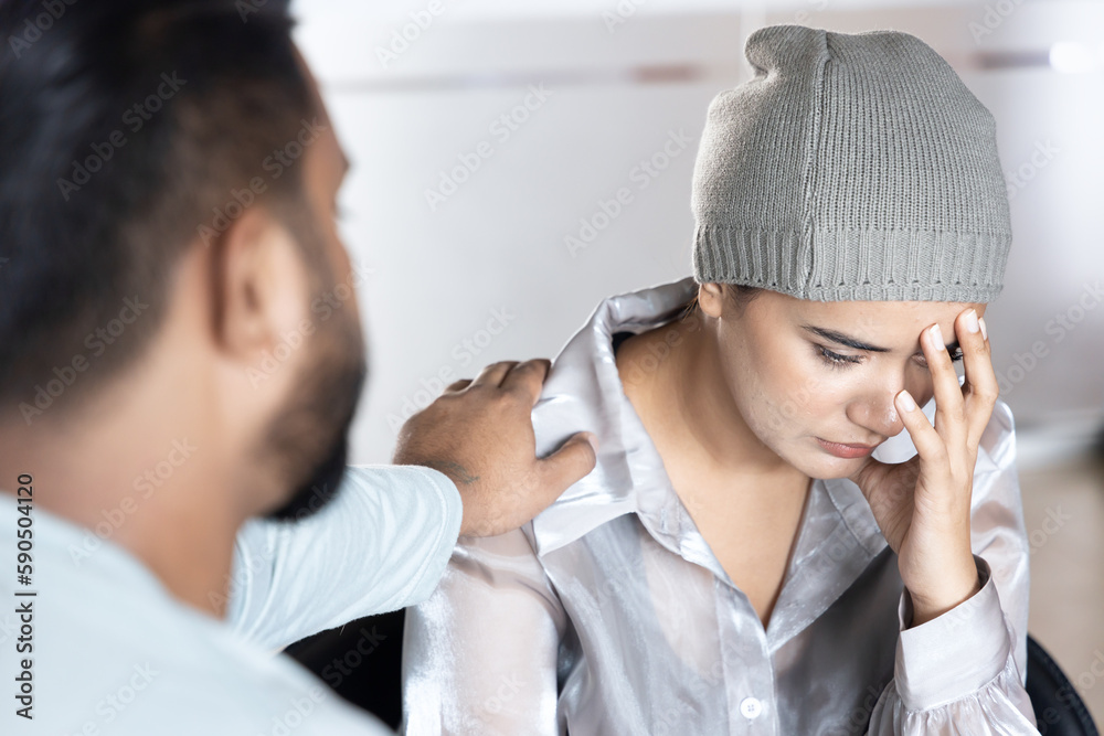 Sad and depressed south asian woman cancer patient with concealing head scarf, suffering from serious hair loss due to chemotherapy negative side effect but having family staying together for support Sad and depressed south asian woman cancer patient with concealing head scarf, suffering from serious hair loss due to chemotherapy negative side effect but having family staying together for support
