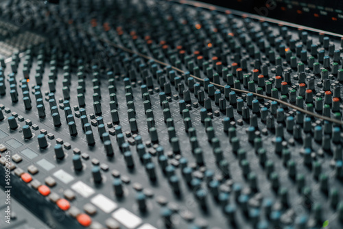 A recording studio control panel mixer with an equalizer faders buttons for broadcasting a recording of a song