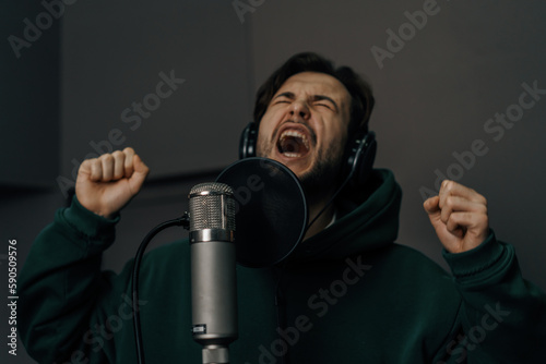 singer with headphones and microphone emotionally recording a new song in a professional recording studio