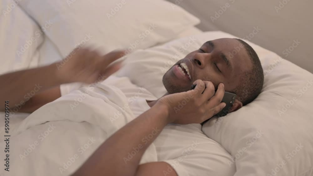 African Man Talking on Phone in Bed African Man Talking on Phone in Bed