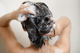 woman taking shower and washing hair with shampoo