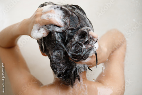 woman taking shower and washing hair with shampoo