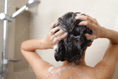 woman taking shower and washing hair with shampoo