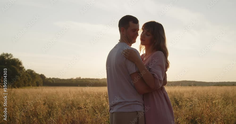 Young attractive couple spend time together at sunset in a golden wheat field. A guy and a girl walk holding hands during the golden hour. Husband and wife are having a date in the summer field. Young attractive couple spend time together at sunset in a golden wheat field. A guy and a girl walk holding hands during the golden hour. Husband and wife are having a date in the summer field.