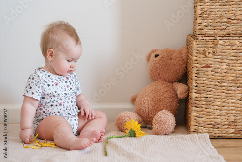 Toddler baby plays with a yellow gerber flower