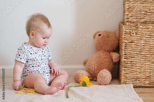 Billede på lærred Toddler baby plays with a yellow gerber flower