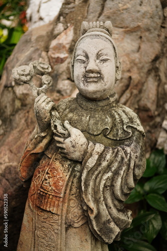 Ancient sandstone sculptures dressed like Chinese people in various poses at Wat Pho, Bangkok, Thailand.