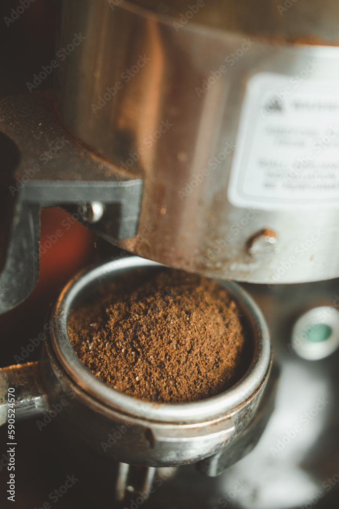 Fresh coffee pouring out of a coffee grinder into a portafilter for a professional espresso machine. Close up Fresh coffee pouring out of a coffee grinder into a portafilter for a professional espresso machine. Close up