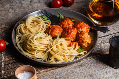 Pasta with meatballs and sauce in a plate on a wooden table