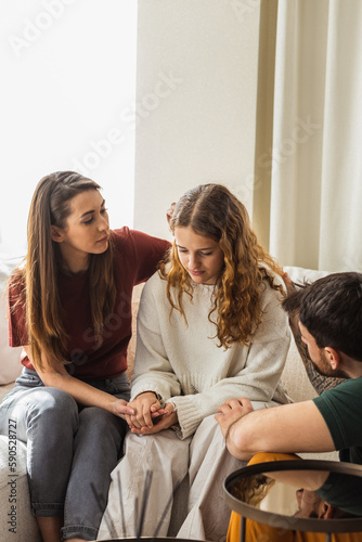 Teenage girl feeling sad while her mom and dad try to comfort her.