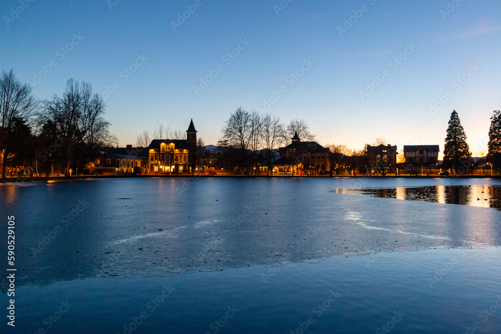 Frozen lake at sunset next to some houses