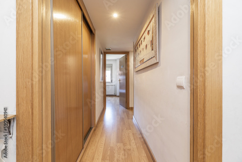 Corridor of a residential house with oak wooden doors, fitted wardrobes and matching flooring