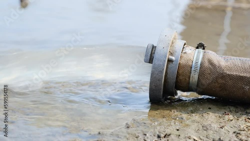 Wastewater sewage pipe dumps the dirty contaminated water into the river. Water pollution, environment contamination concept.