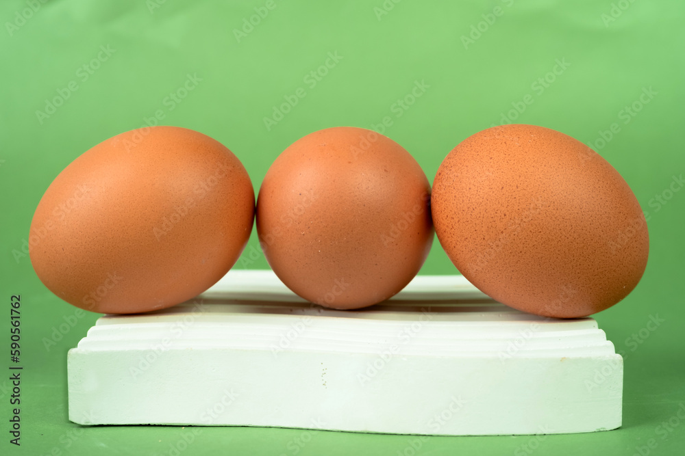 Fototapeta premium Chicken eggs on a white coaster on a green background.