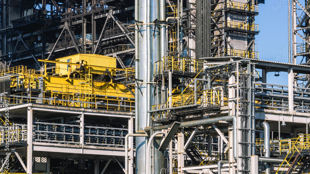 Oil refining plant. Technological equipment for the production of fuel components. White smoke escapes into the atmosphere from the production equipment at the refinery. White smoke and blue sky.