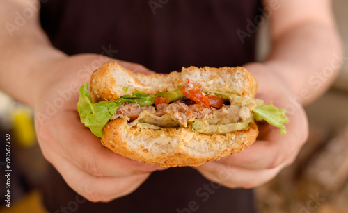 Yummy homemade burgers in hand. Sesame bun, green salad, pork cutlet.
